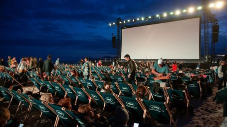 An overview of an open-air movie screening with many people already seated, signifying Pune International Film Festival