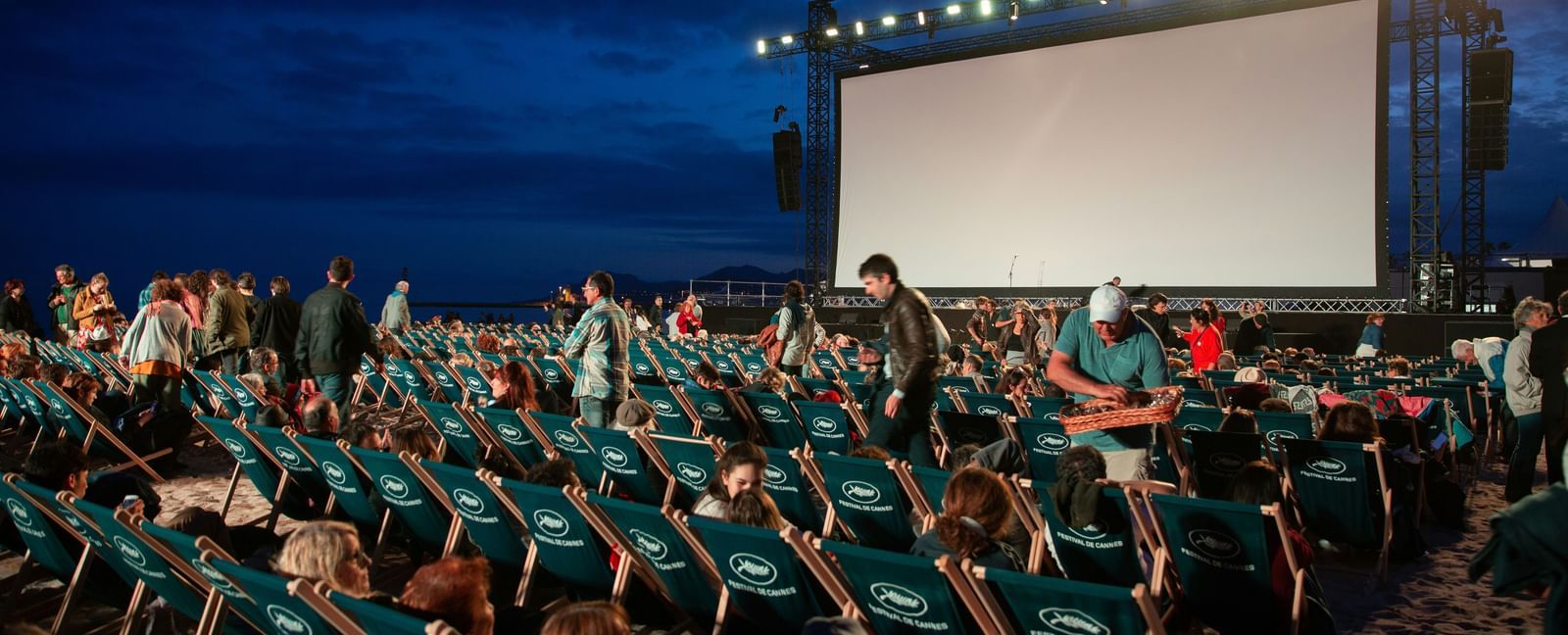 An overview of an open-air movie screening with many people already seated, signifying Pune International Film Festival