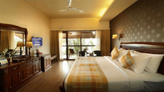 The Ocean Breeze Suite at Uday Samudra Leisure Beach Hotel offers a king size bed, a dressing table, a television, and a balcony as the daylight makes its way in through the large windows