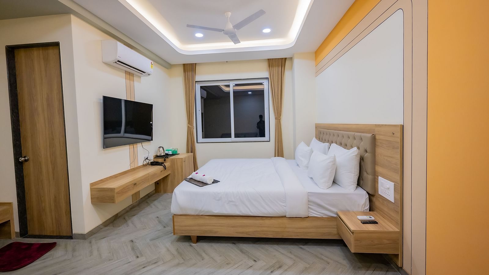 A spacious hotel suite with a large bed, seating area, and sleek TV unit at Lotus Leaf Boutique Hotel.