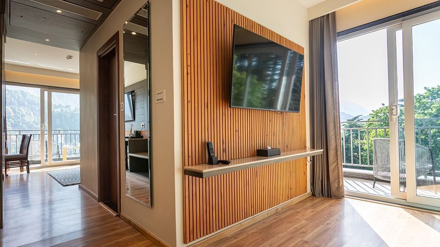 An image of a Suite with a flat screen TV, a full length mirror, and an expansive glass door leading to the balcony - The Belvedere Himalayan Retreat, McLeodganj