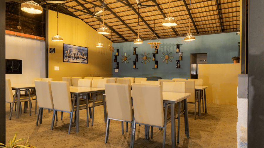 High-ceiling resort restaurant dining hall with wooden rafters, warm hanging lights, and neatly arranged tables.