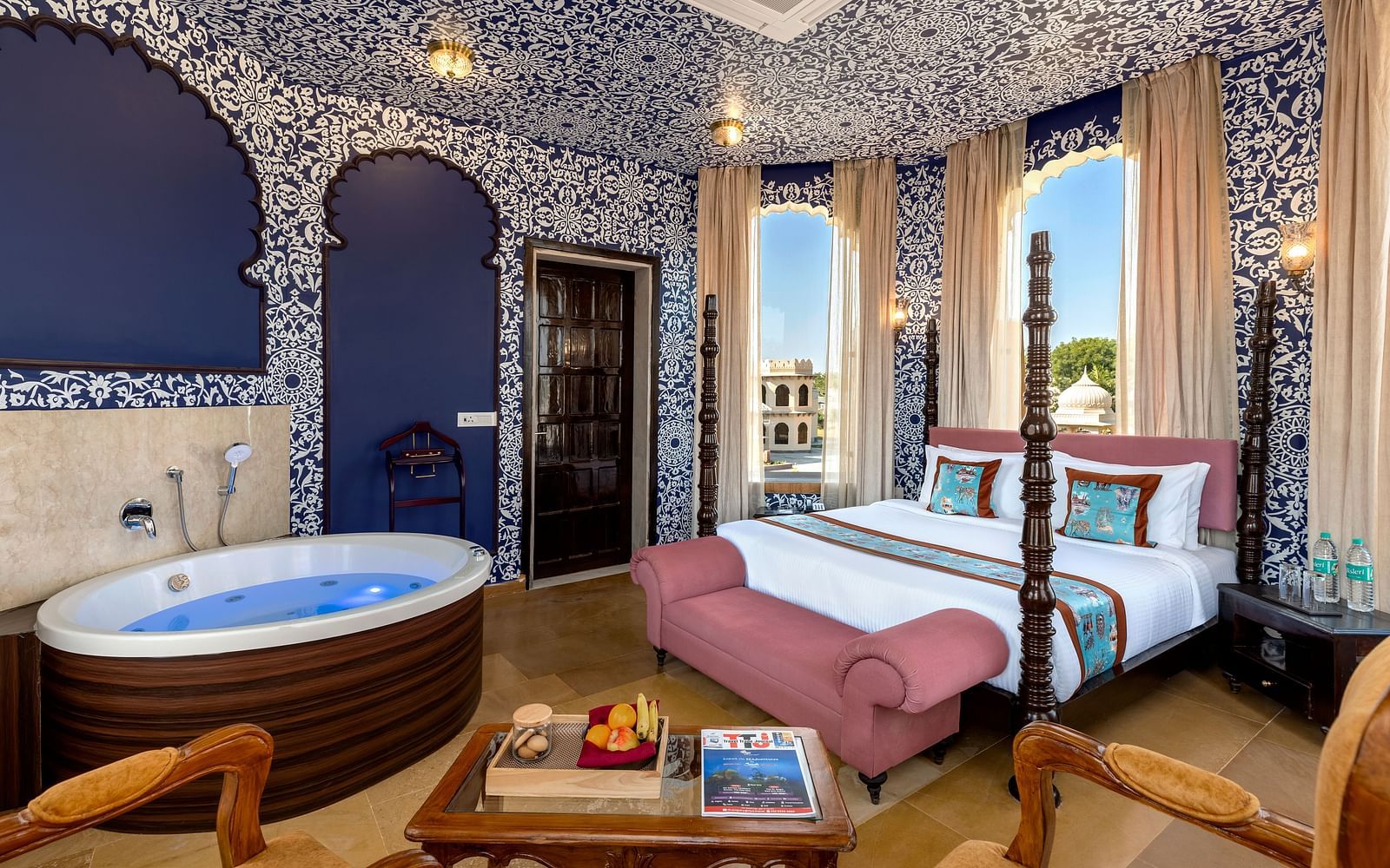 Heritage-style bedroom with ornate blue interiors, canopy bed, and in-room hot tub at Kesar Bagh Palace.