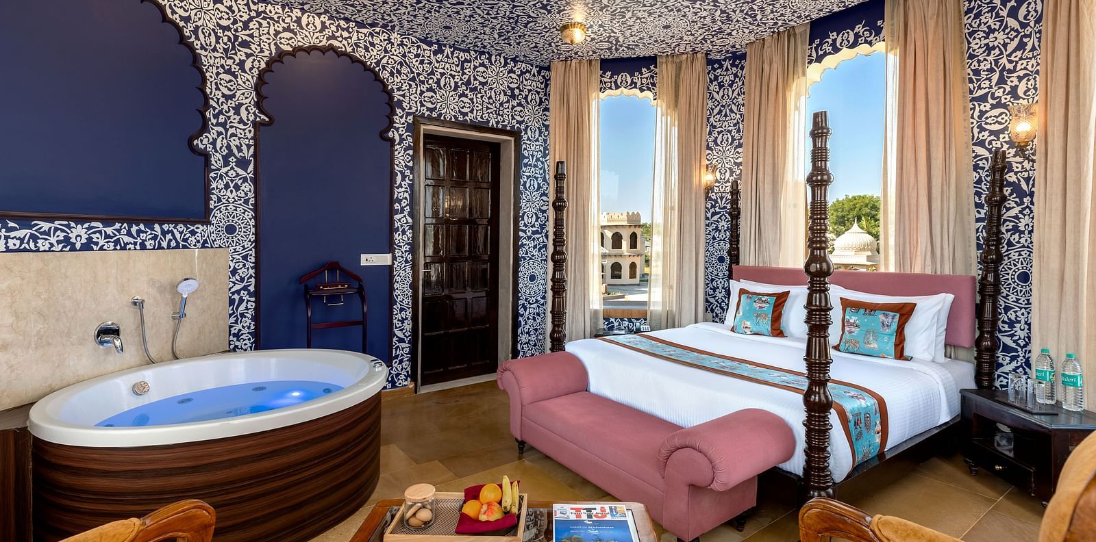 Heritage-style bedroom with ornate blue interiors, canopy bed, and in-room hot tub at Kesar Bagh Palace.
