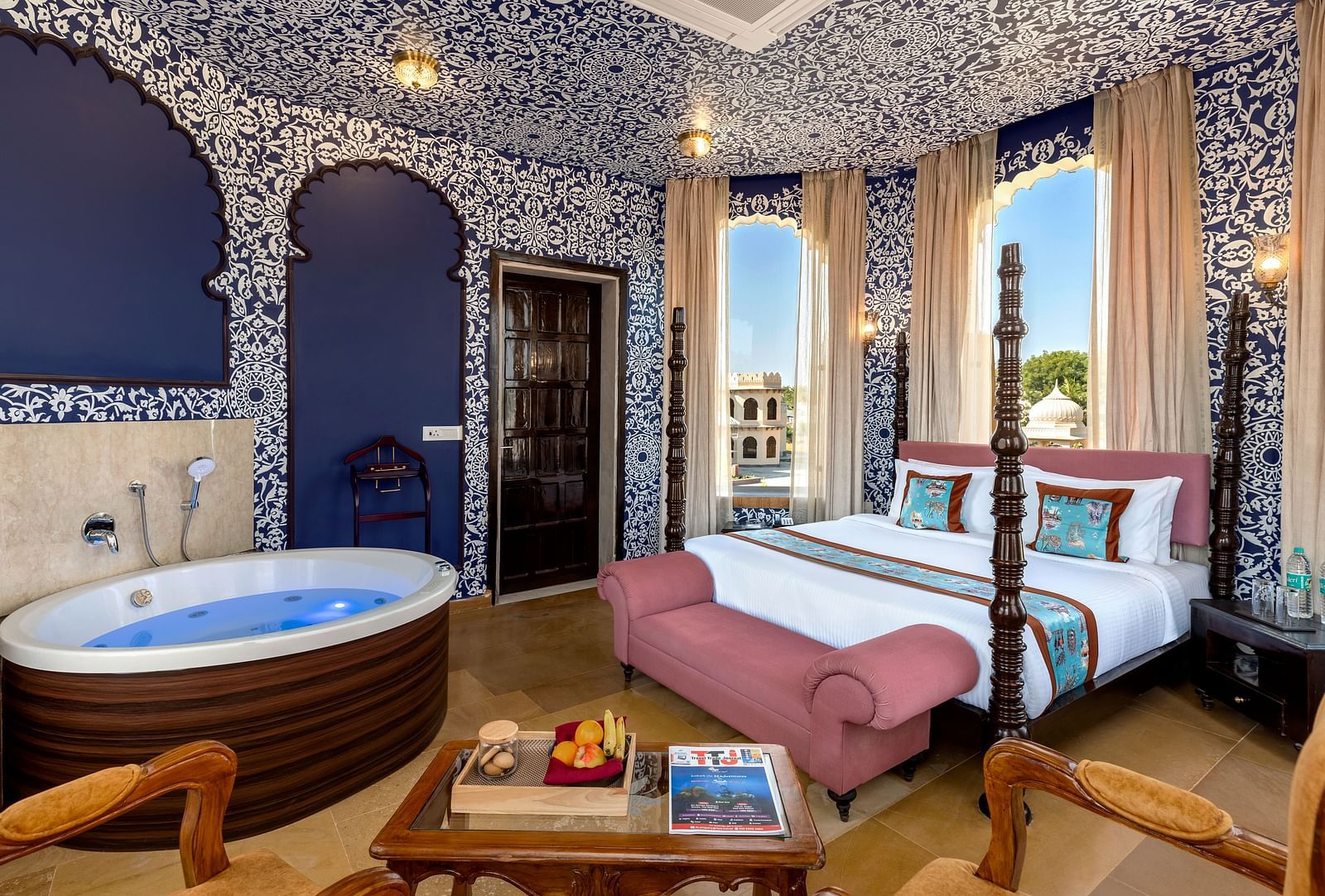Heritage-style bedroom with ornate blue interiors, canopy bed, and in-room hot tub at Kesar Bagh Palace.