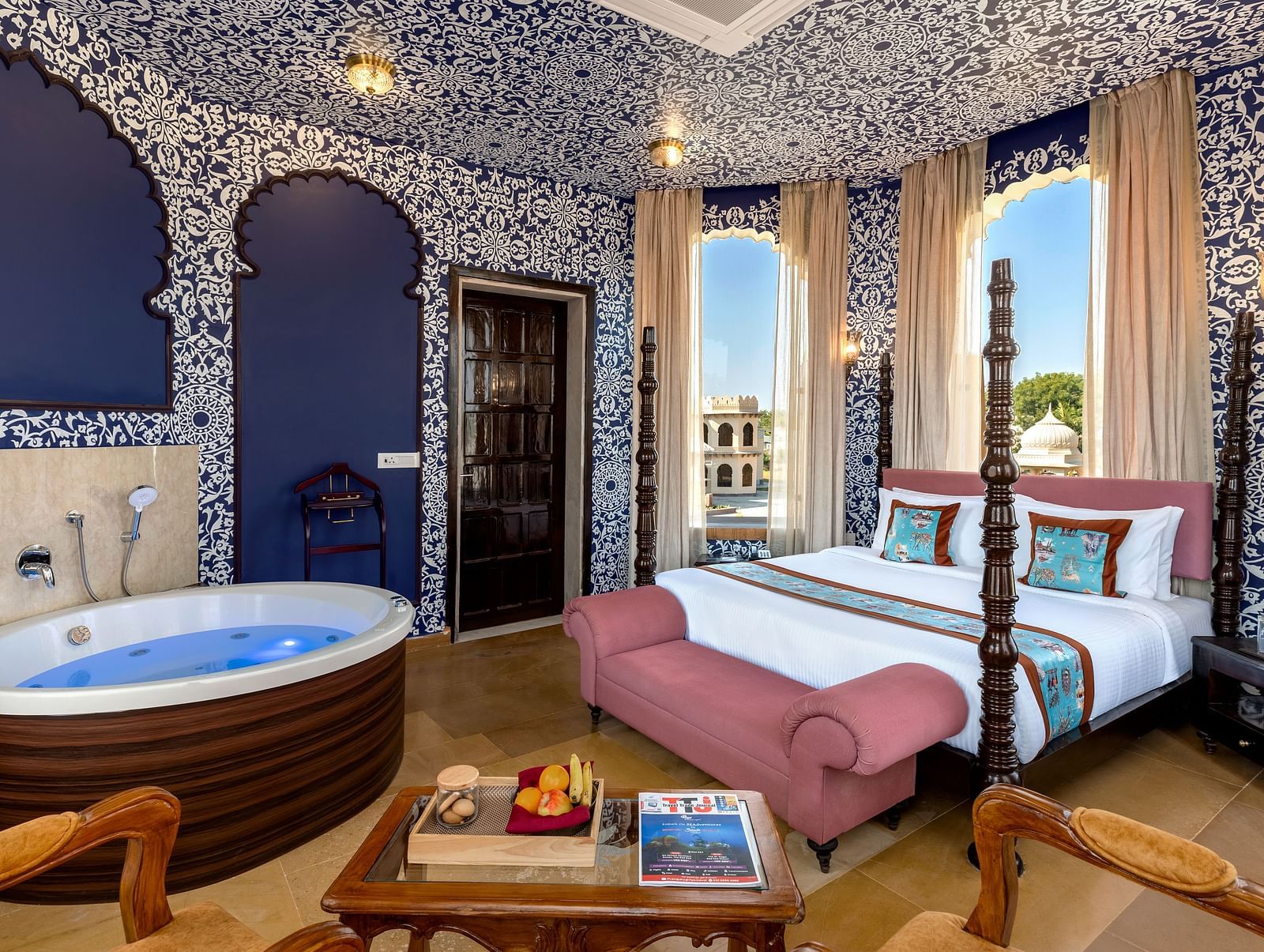 Heritage-style bedroom with ornate blue interiors, canopy bed, and in-room hot tub at Kesar Bagh Palace.
