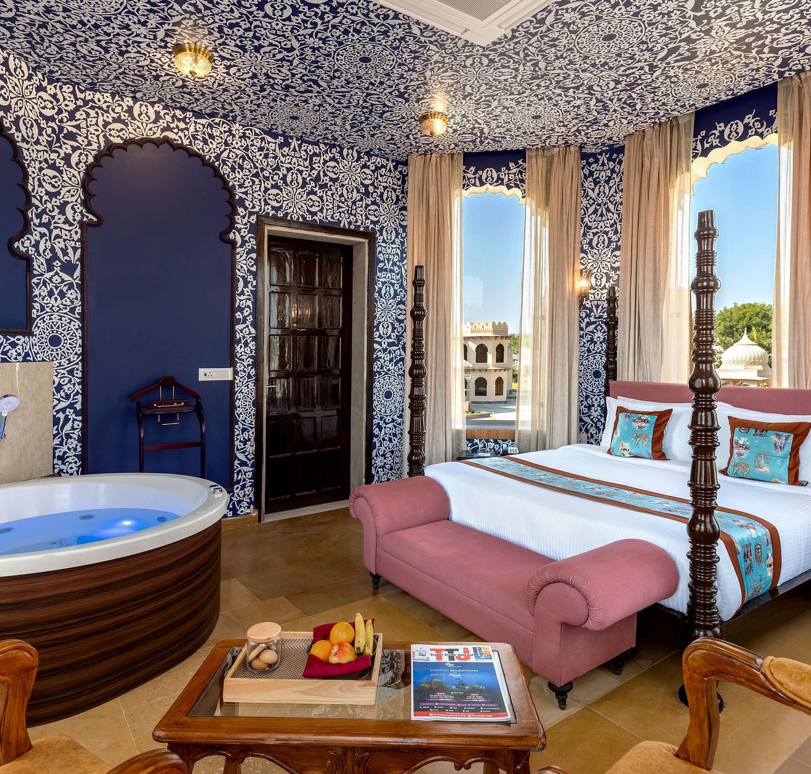 Heritage-style bedroom with ornate blue interiors, canopy bed, and in-room hot tub at Kesar Bagh Palace.