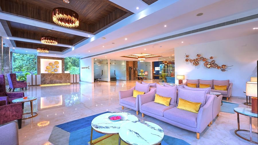An image of a hotel lobby with plush couches placed in front of round coffee tables - Golden Tulip, Agra