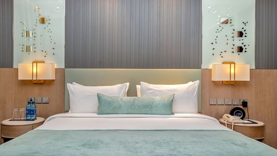 A bedroom featuring a large comfortable bed with decorative accents at Neelkanth Sarovar Premiere Lusaka