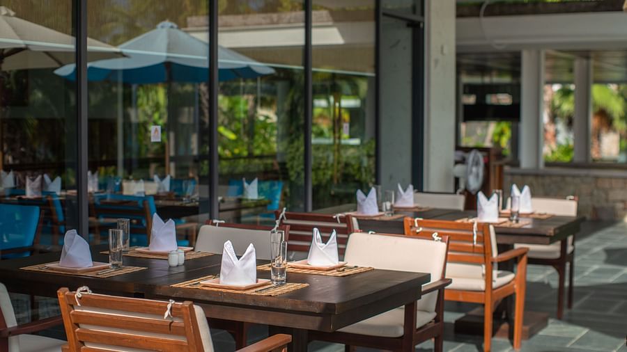 An outdoor sitting area with wooden chairs and tables- Alibu Resorts Nha Trang