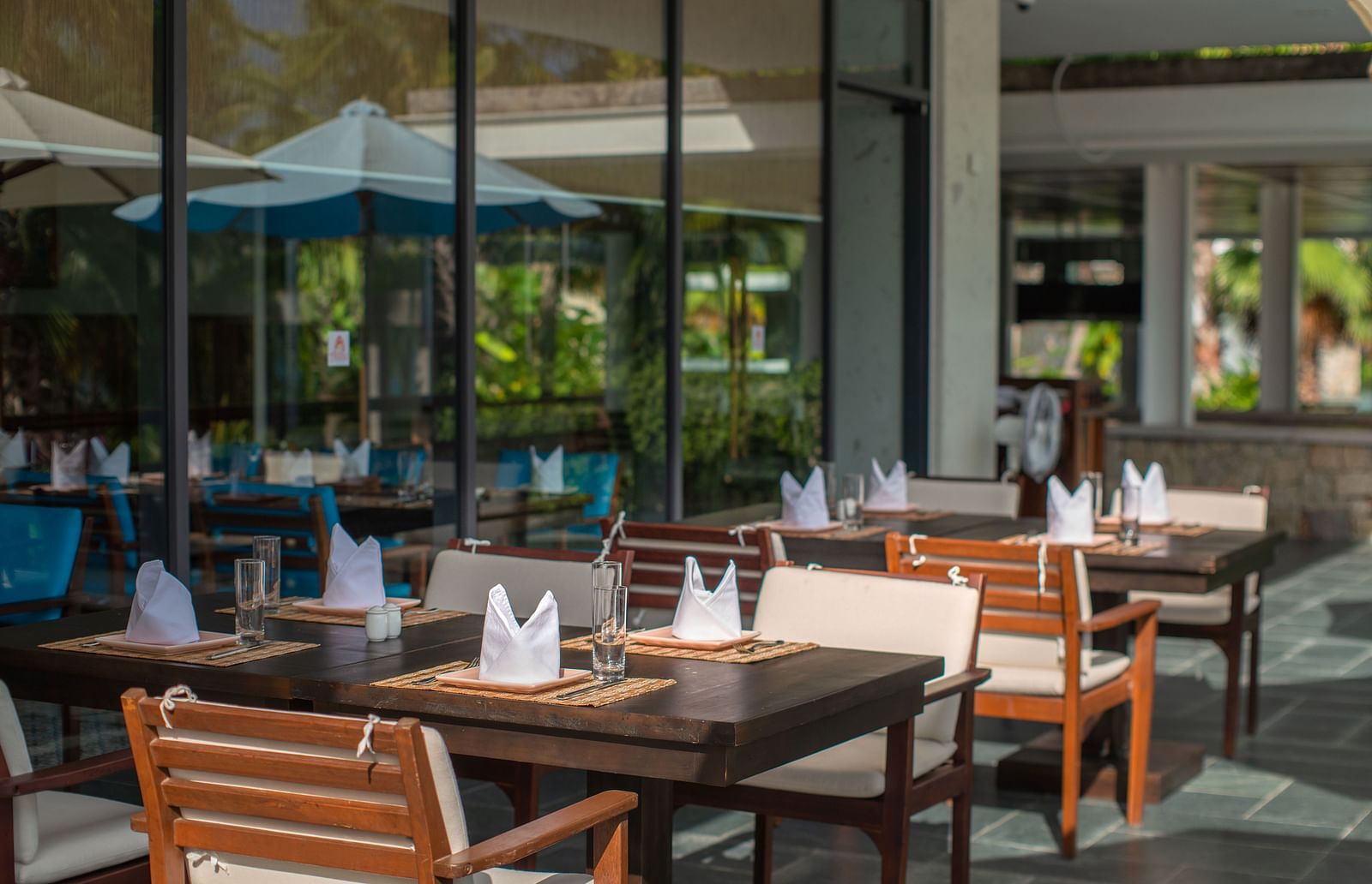 An outdoor sitting area with wooden chairs and tables- Alibu Resorts Nha Trang