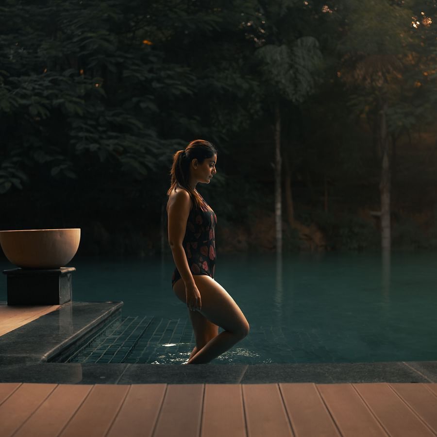 A woman standing at the edge of the swimming pool at The Ananta Udaipur, preparing to dive in.