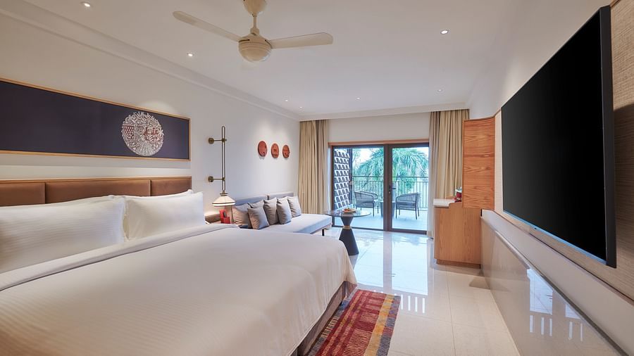 A bedroom with a king bed, tv, a balcony overlooking greenery at The Dukes Retreat.