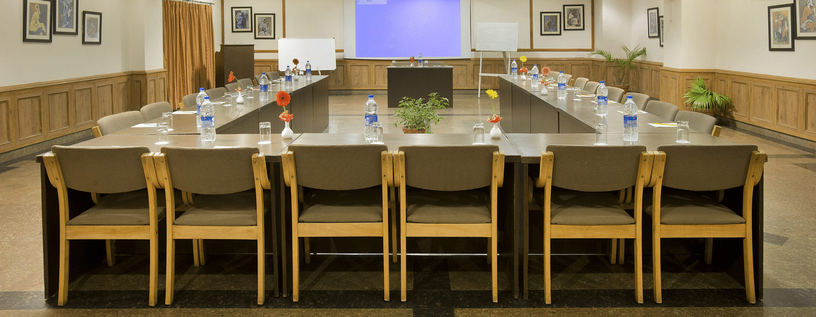 a front view of a conference room with a U-shaped seating arrangement and the projector on the other end of the room