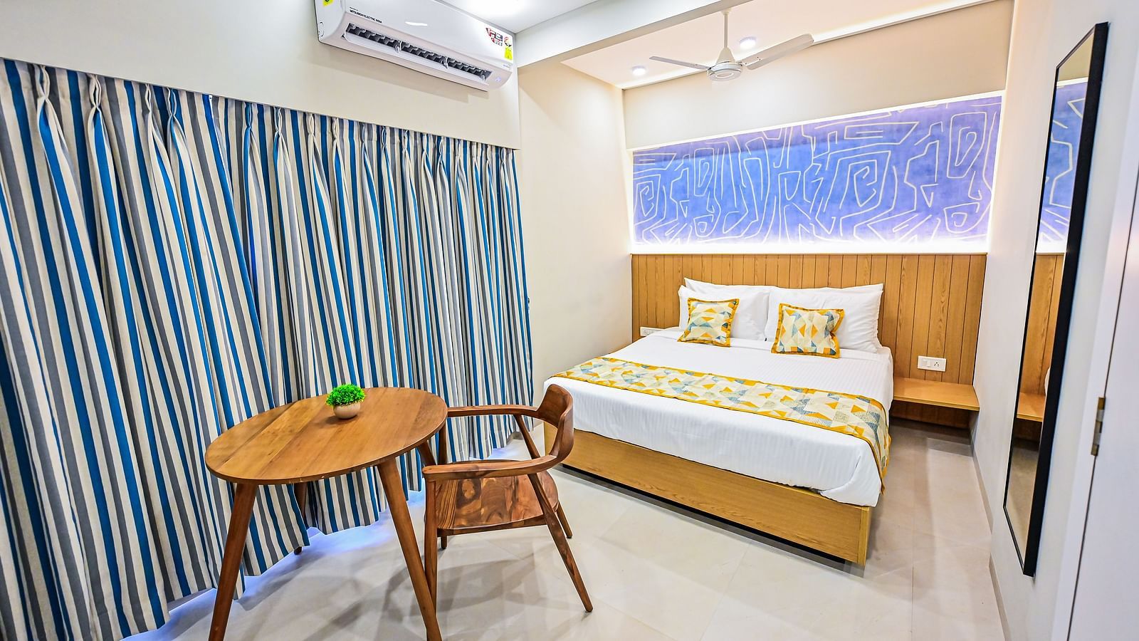 An image of a bedroom featuring a double size bed, AC, a table and chair, and a mirror attached to the wall at Indie Stays Studio, Chembur