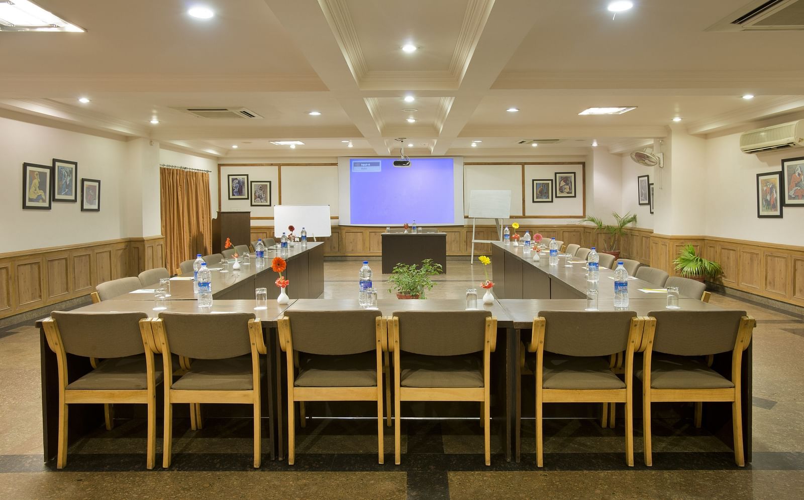 a front view of a conference room with a U-shaped seating arrangement and the projector on the other end of the room