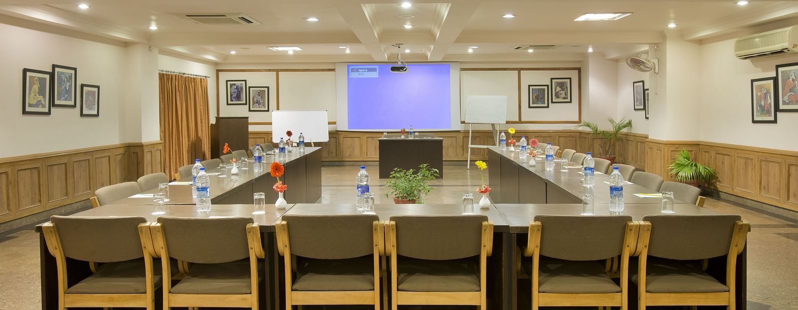 a front view of a conference room with a U-shaped seating arrangement and the projector on the other end of the room