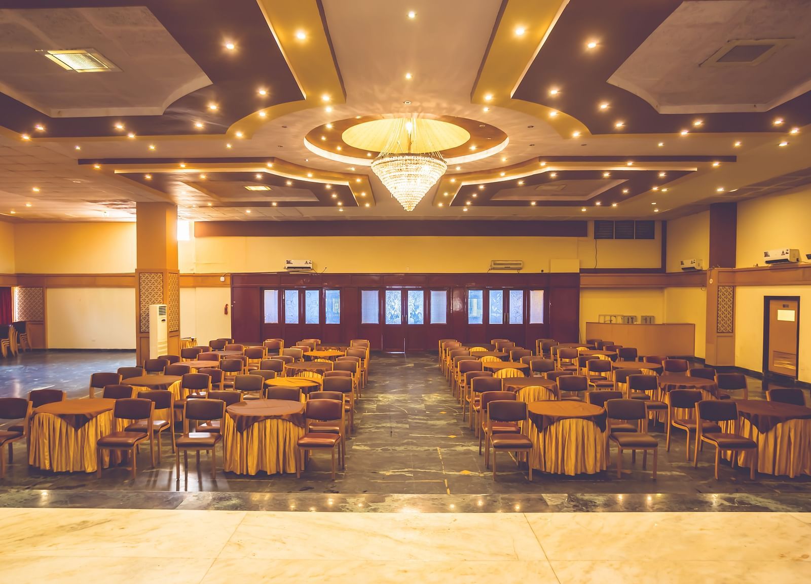 Interiors of a banquet hall at Paradise Isle Beach Resort, Udupi with a chandelier and theatre style seating under it