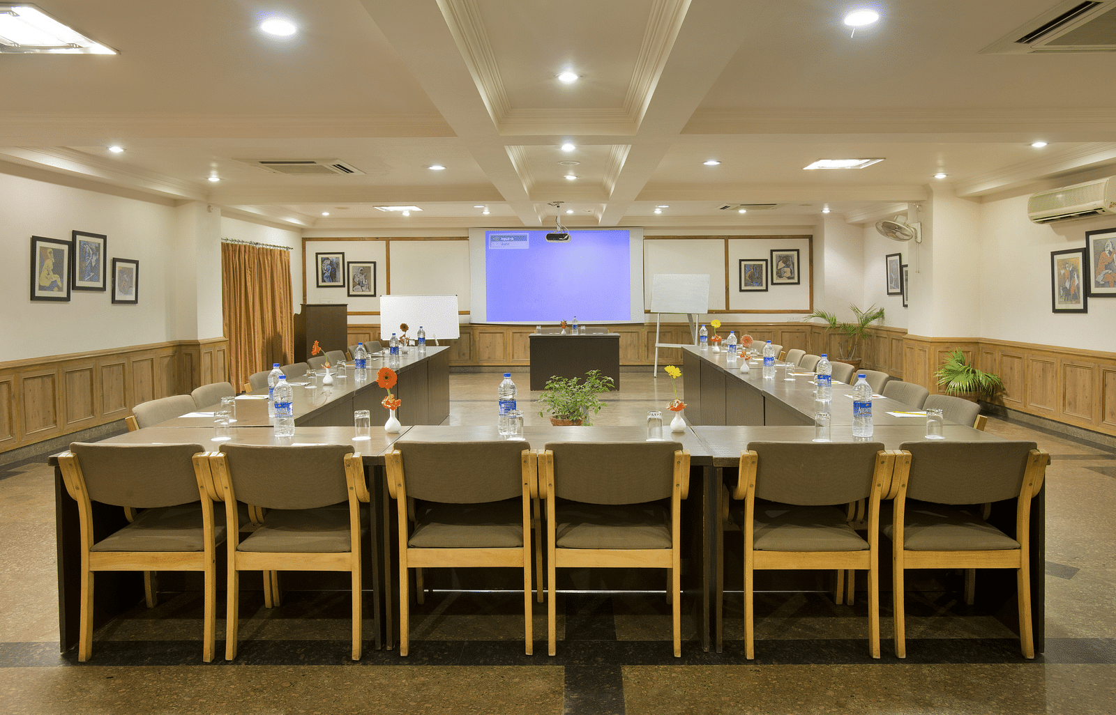 a front view of a conference room with a U-shaped seating arrangement and the projector on the other end of the room