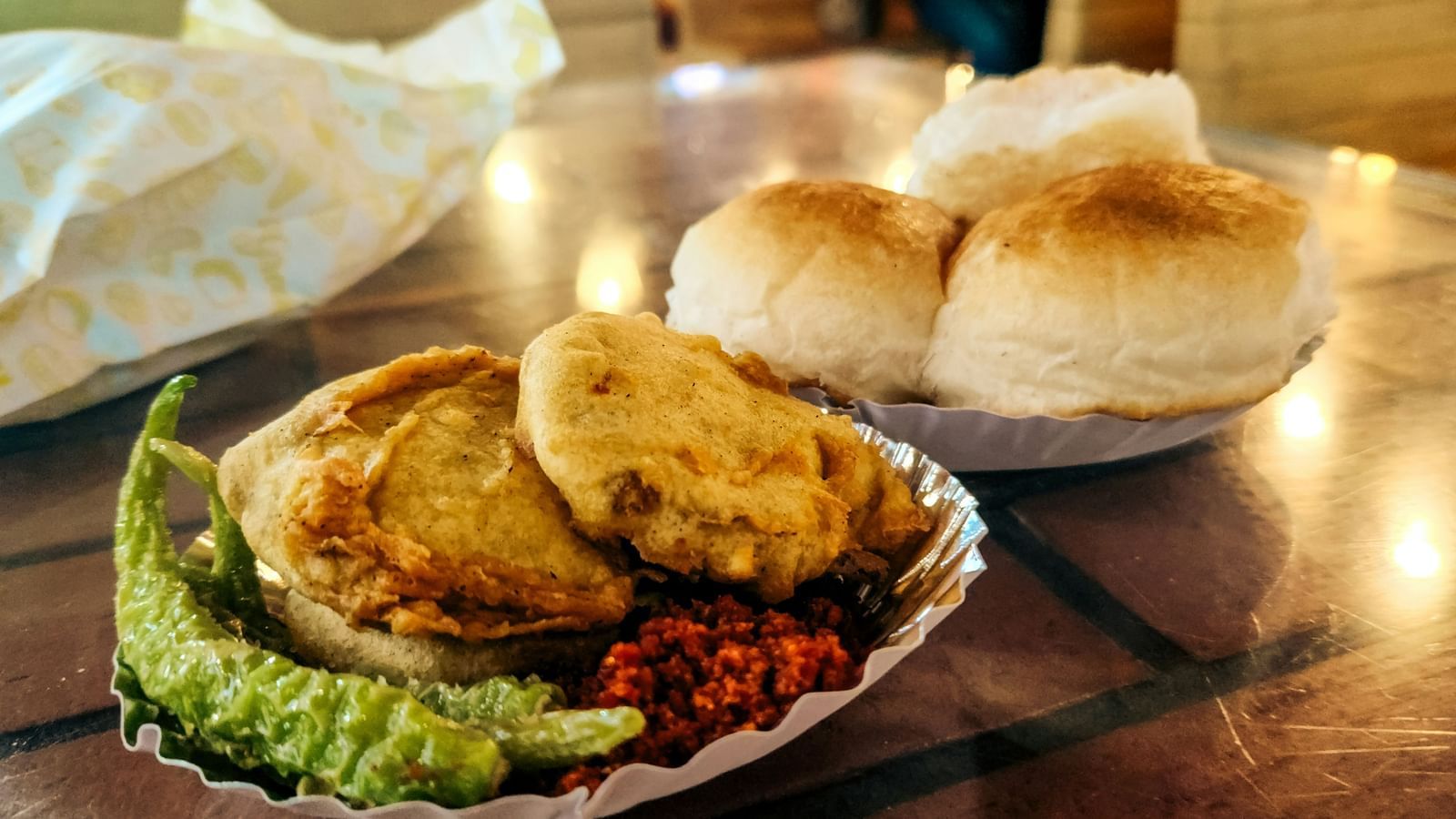 A close up of a plate of Vada Pav with a chili on the side, this is by far the Best Street Food in Udaipur.