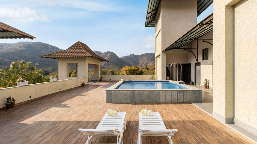 A huge verandah area featurin a small swimming pool enclosure, along with 2 sun loungers in the foreground at The Hunting Lodge.
