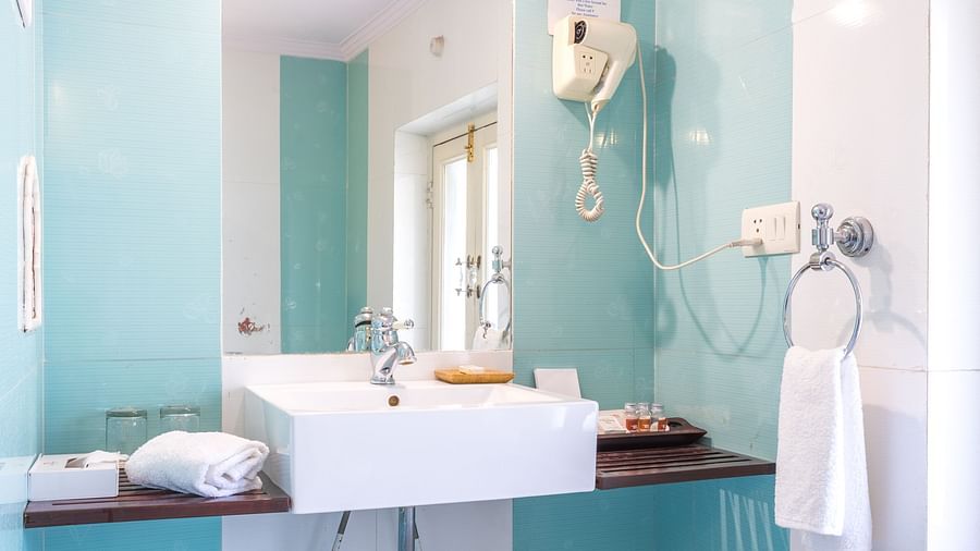 A sink with a mirror and hair dryer in the bathroom of deluxe rooms - Mandawa Haveli, Jaipur