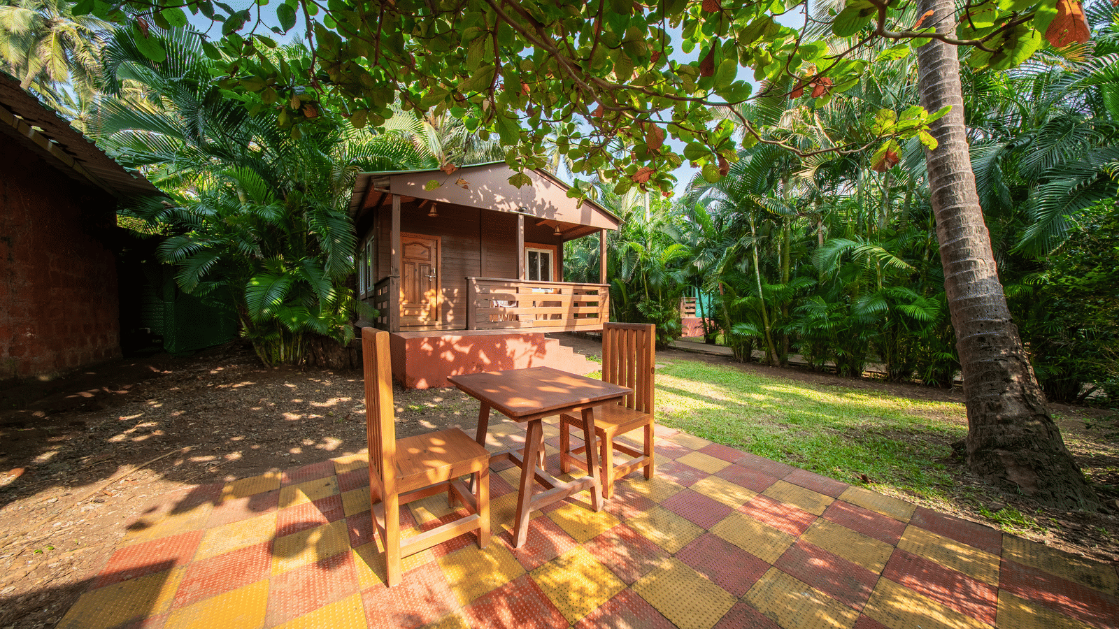 Wooden treehouse on stilts under trees, play area at Tranquil Beach Resort, Harihareshwar.
