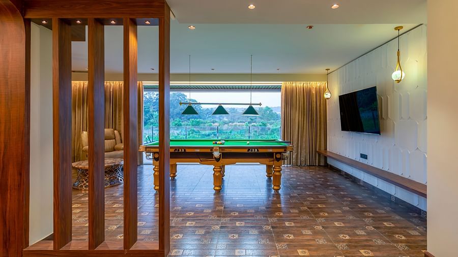 a pool table in the living room with a tv wall mounted next to it inside one of the rooms - The Tanisi Hotels & Resorts, Goa