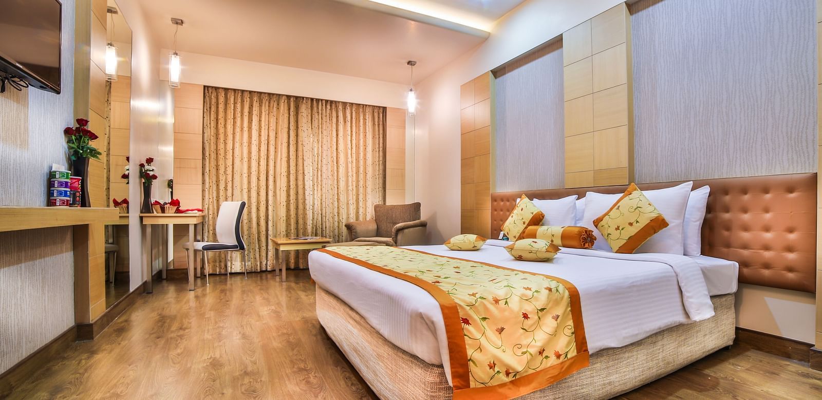 A modern hotel bedroom with a large bed, gold and white bedding, and elegant wood paneling A grand hotel suite with an opulent red and white decor, large bed, and seating area, reflecting a traditional style at Sitara Luxury Hotel in Hyderabad near Ramoji 