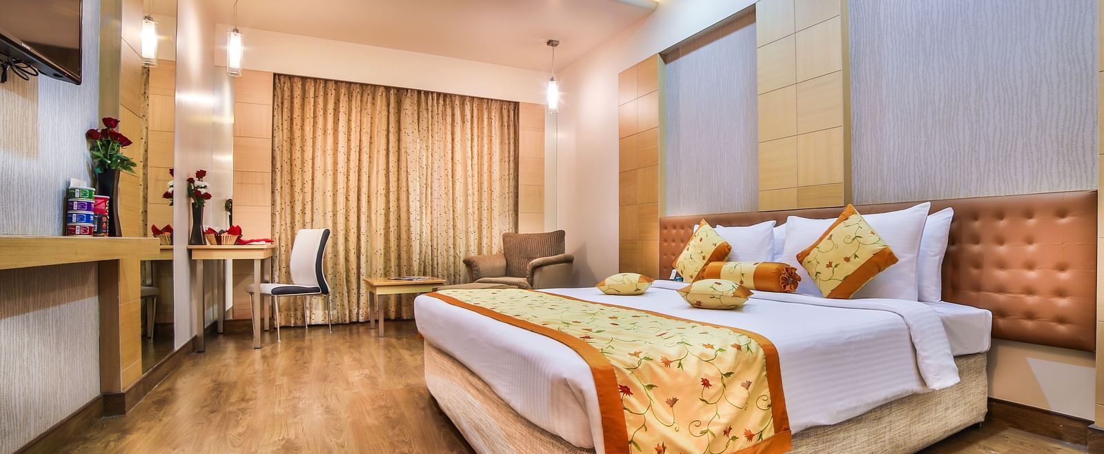 A modern hotel bedroom with a large bed, gold and white bedding, and elegant wood paneling A grand hotel suite with an opulent red and white decor, large bed, and seating area, reflecting a traditional style at Sitara Luxury Hotel in Hyderabad near Ramoji 