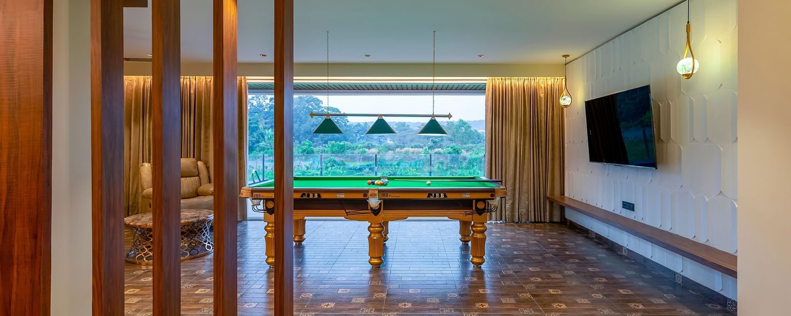 a pool table in the living room with a tv wall mounted next to it inside one of the rooms - The Tanisi Hotels & Resorts, Goa