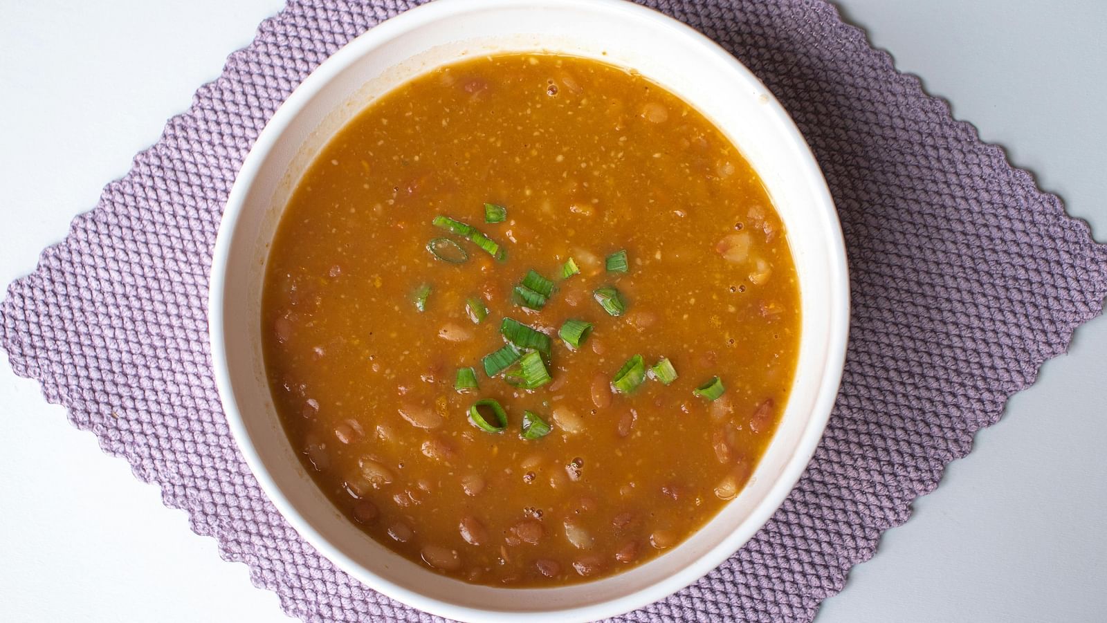 A steaming bowl of dal garnished with fresh coriander, served on a table.