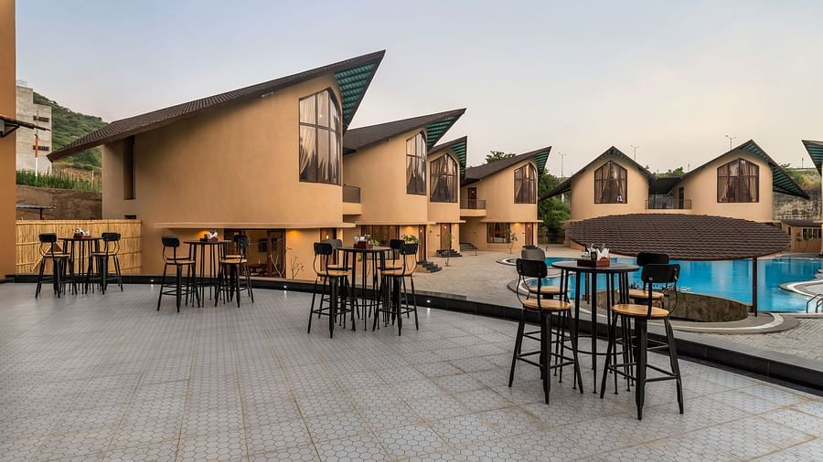 Exterior of Rhythm & Brews at dusk, showcasing modern architecture, outdoor seating areas, and a swimming pool at The Qualia Resort Club & Brewery, Udaipur.