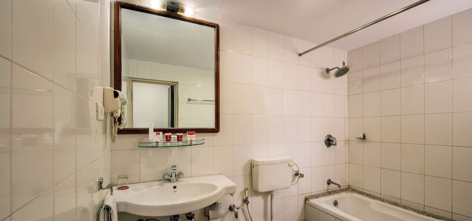 A bright hotel bathroom with a sink, toilet, and a bathtub with a shower - Lords Eco Inn Dahej