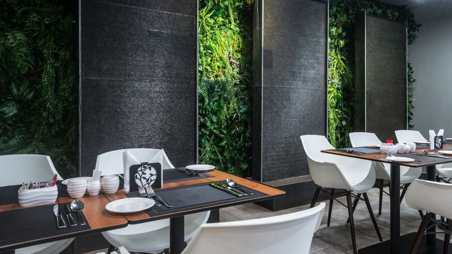 Bright contemporary restaurant dining area with greenery walls and modern white chairs at Best Western Premier Westlands hotel.