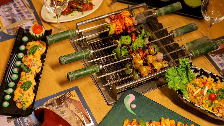 An image of a barbecue grill set up along with several other platter where grilled foot items are served at Themis Barbecue House, NSP Pitampura