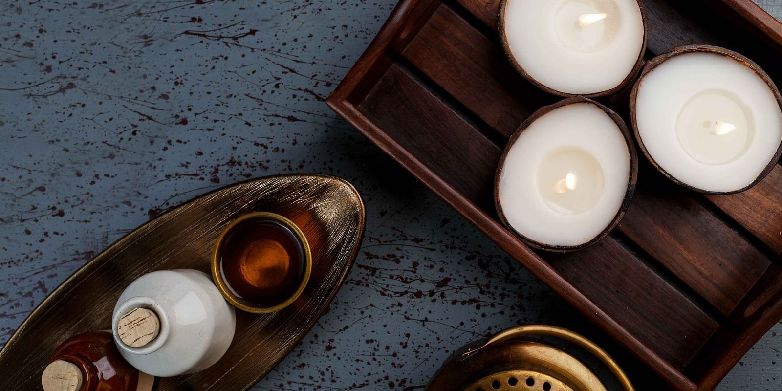 An assortment of decorative candles and a metallic object arranged on a dark, textured surface.