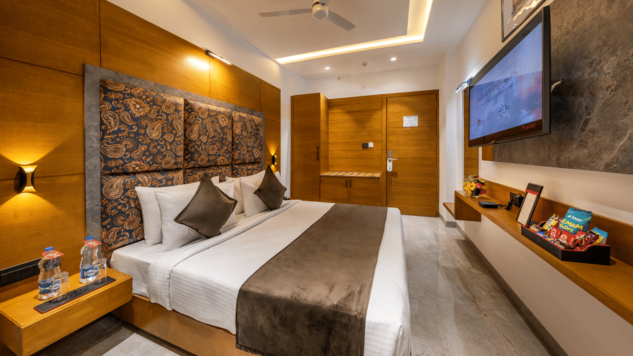 Elegant Deluxe room with Double bed, modern lighting, premium wooden interiors and a TV .