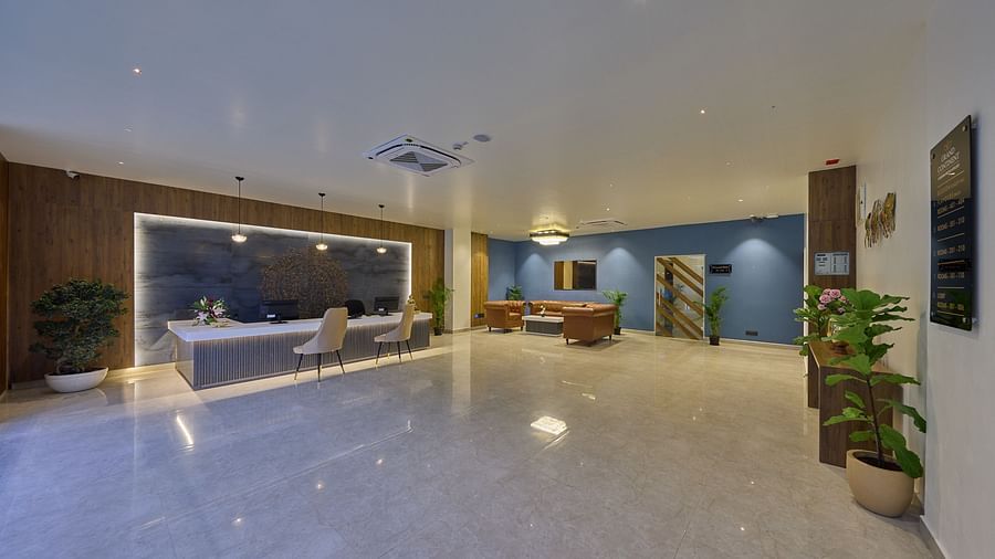 Another angle of our hotel lobby with a reception desk, potted plants and a sitting area filled with orange couches