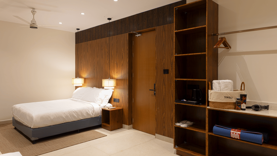 Bedroom at SUKAVI with a large bed, wooden storage units, and warm indoor lighting arranged around the sleeping area.