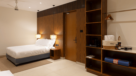 Bedroom at SUKAVI with a large bed, wooden storage units, and warm indoor lighting arranged around the sleeping area.