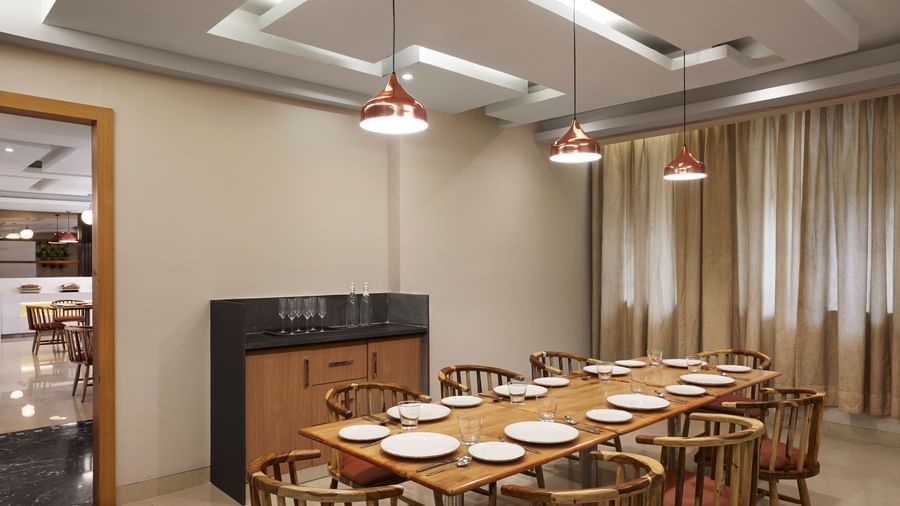 A long dining table set with plates in a conference or private dining room at Monday Hotels Mahape, Navi Mumbai.
