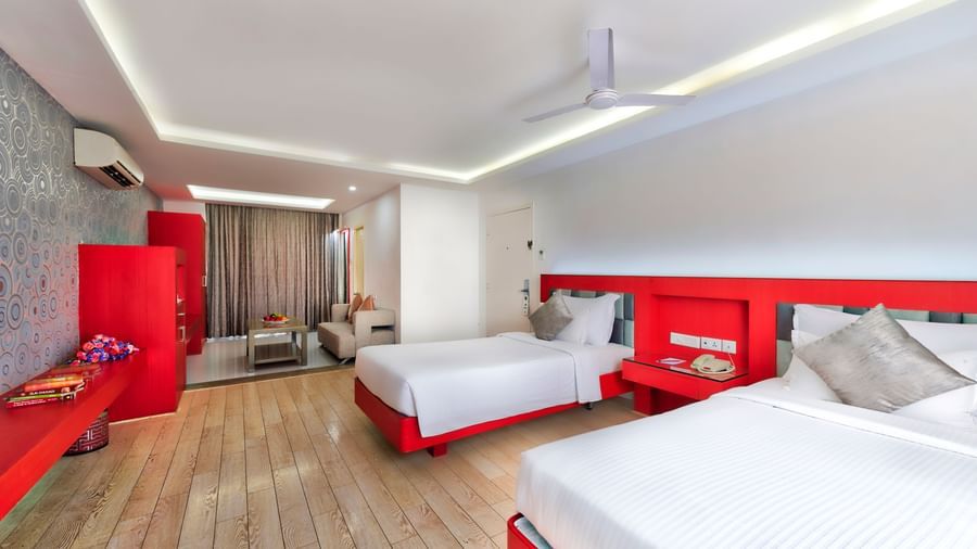 A hotel bedroom with a white bed, red headboard, and a seating area with a white sofa | Grande Chalet | Grande Bay Resort & Spa, Mamallapuram