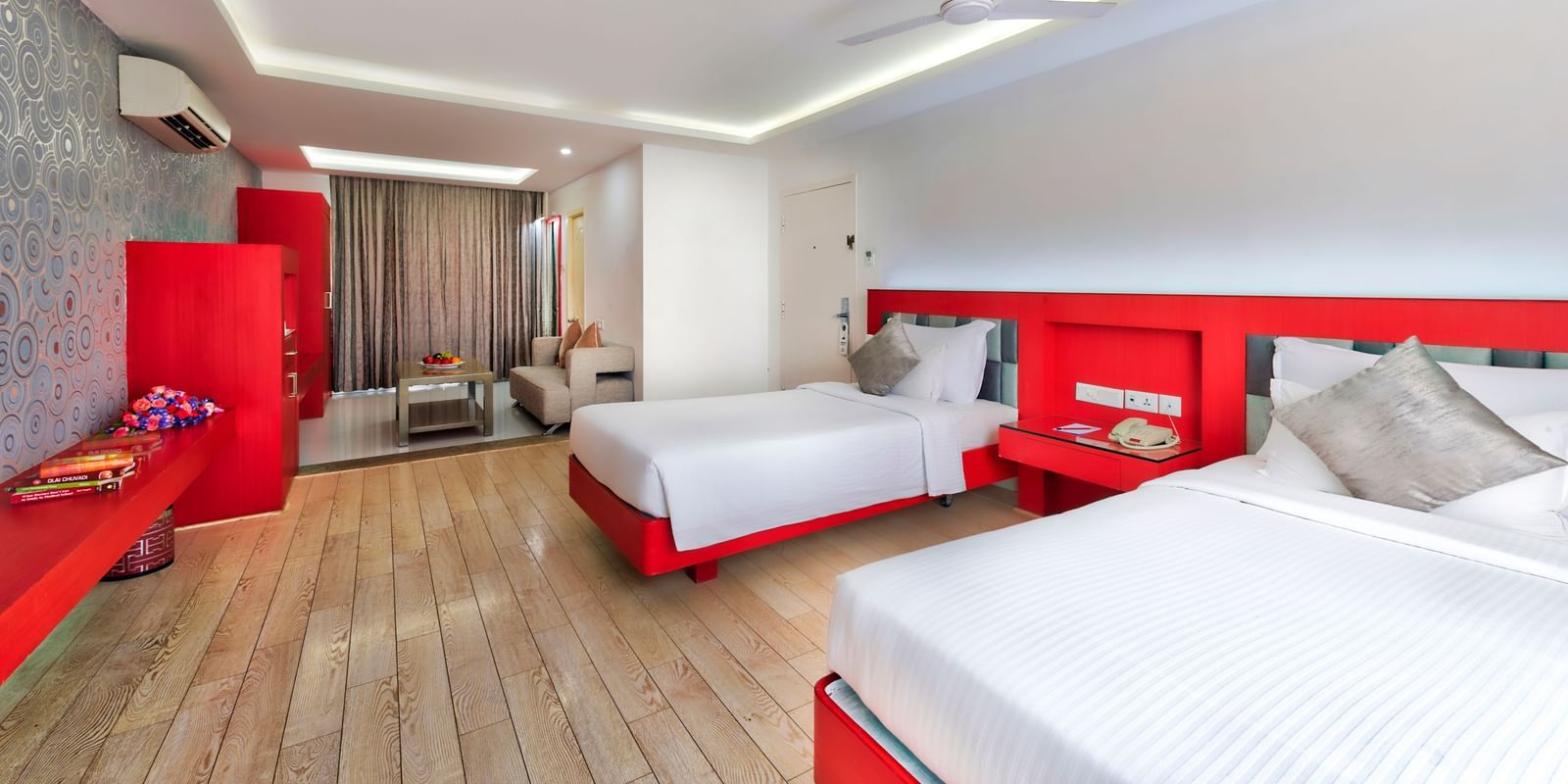 A hotel bedroom with a white bed, red headboard, and a seating area with a white sofa | Grande Chalet | Grande Bay Resort & Spa, Mamallapuram