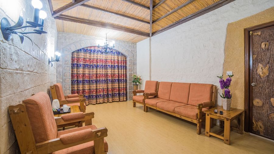 A traditional sitting area with rustic furniture, warm lighting, and a checkered windowpane at  Sitara Luxury Hotel in Hyderabad near Ramoji Film City.
