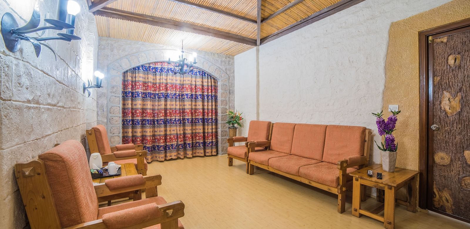 A traditional sitting area with rustic furniture, warm lighting, and a checkered windowpane at  Sitara Luxury Hotel in Hyderabad near Ramoji Film City.