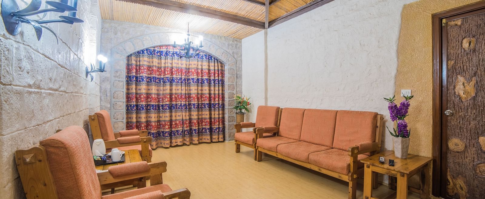 A traditional sitting area with rustic furniture, warm lighting, and a checkered windowpane at  Sitara Luxury Hotel in Hyderabad near Ramoji Film City.