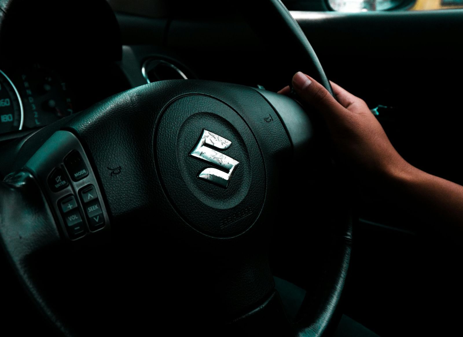 A person's hands grip the steering wheel of a car.