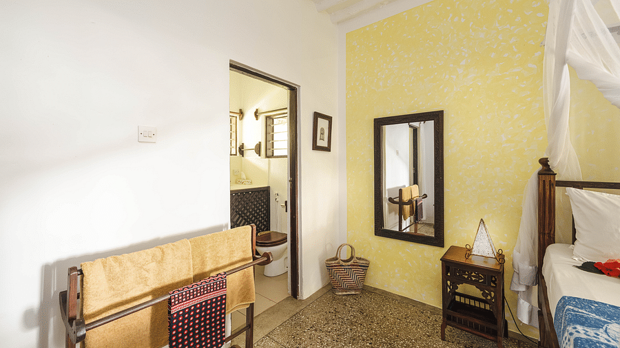 Interior view of a bedroom with a bed with a canopy, a mirror, and a bathroom visible through an open doorway - Shooting Star Boutique Hotel.