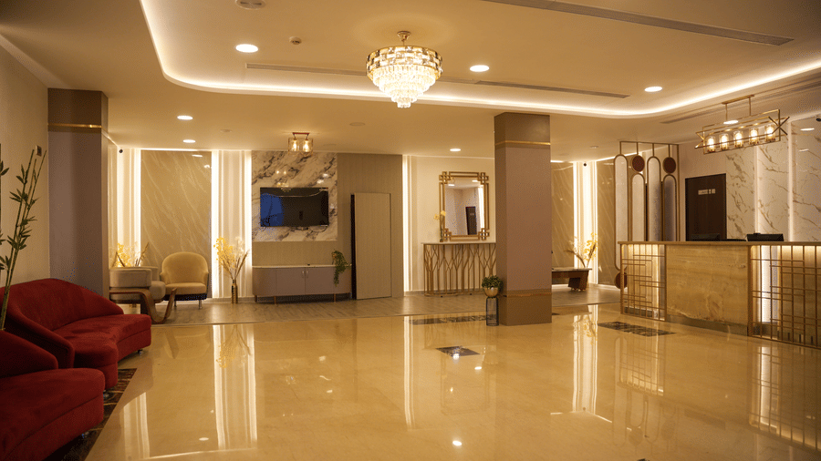 Lobby of The OnTime Bangalore in Ashok Nagar featurig seating area, a huge reception desk, and a flat TV screen. There are other decorative elements like mirror on the wall, ceiling lights, and other fixtures. 